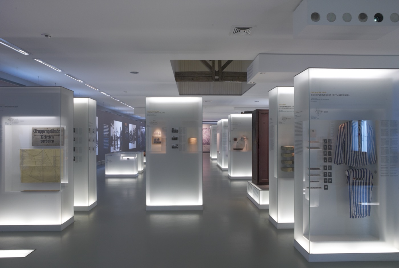 Gedenkstätte Sachsenhausen, Gesamtbild Blick in den Ausstellungsraum mit Vitrinen und Podesten und bedruckten Wandflächen